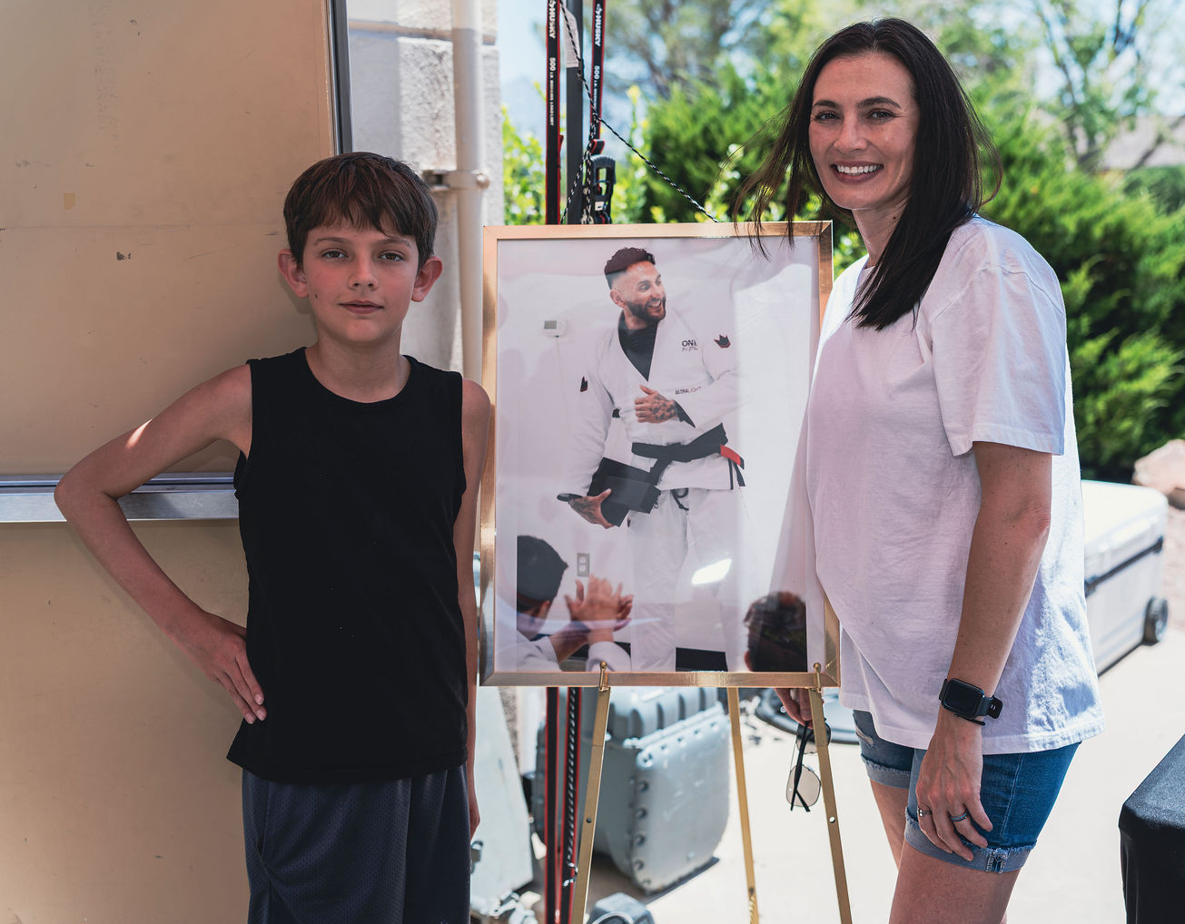 Family members standing beside a framed portrait of Vin at Grounded Strength Academy in Rio Rancho NM