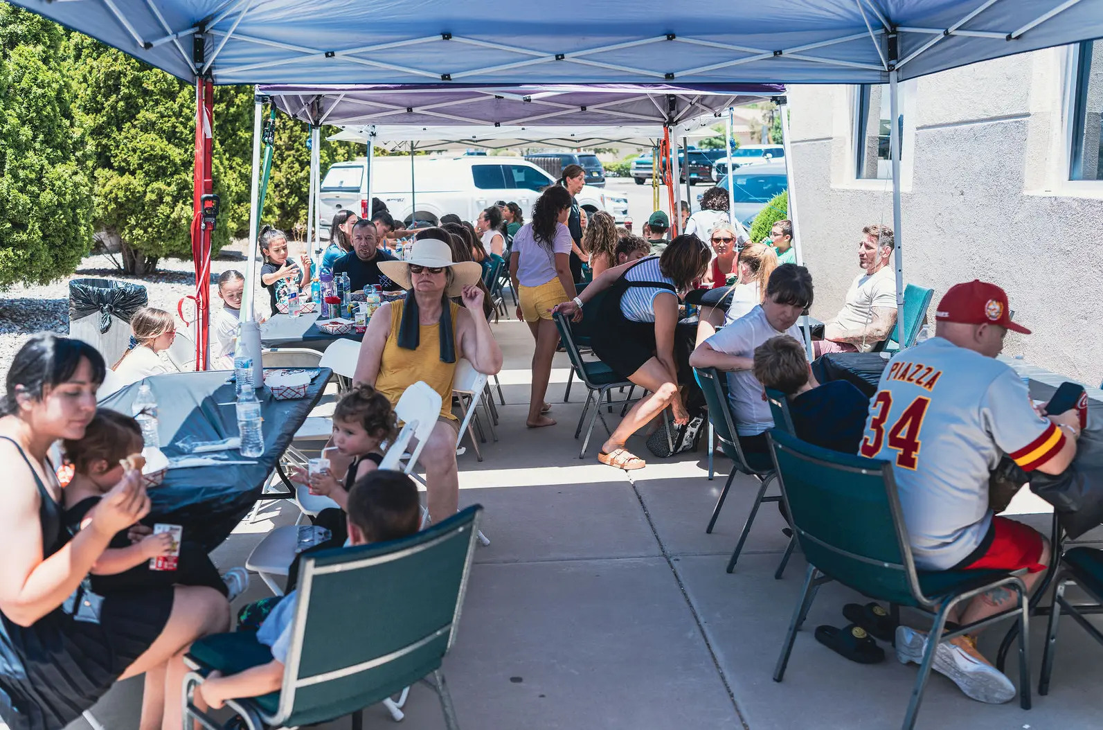 Families gathered under canopies outside Grounded Strength Academy for a community picnic